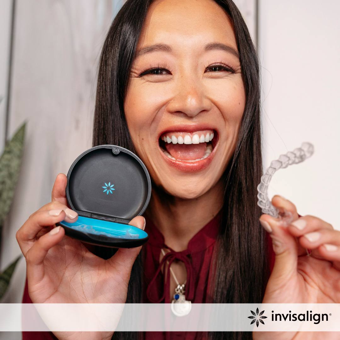 Woman smiling and holding Invisalign aligner